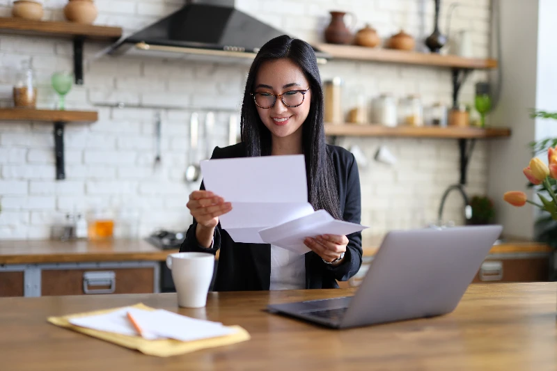 Blog 4 Businesswoman happily reads financial letter at a desk with laptop